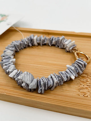 Gray beaded bracelet with gold hoop clasp and textured bead detail