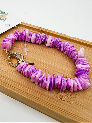 Purple beaded bracelet with gold clasp and small charm