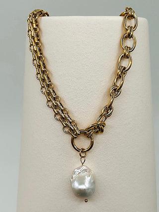 Gold necklace with chunky chain links and a single pearl drop charm