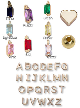 Gold charm alphabet letters A–Z with colored gemstone pendants