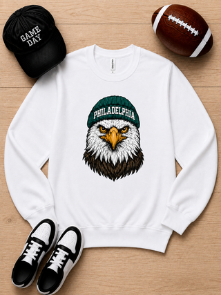 White long sleeve crewneck sweatshirt with Philadelphia graphic eagle face and green cap.