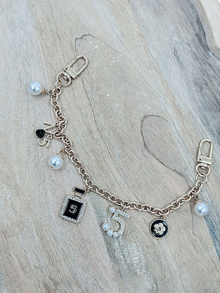 Rose gold bag chain with lock charm pendants, pearl beads, and clasp links
