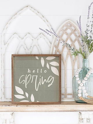 Wood framed hanging sign with “hello spring” script on dark green panel