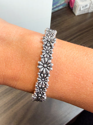 Silver flower bracelet with repeating flower-shaped links on wrist