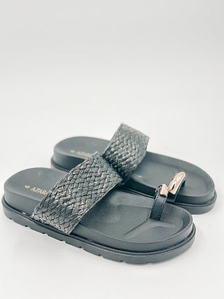 Faux leather slide sandals with dark textured strap, metal buckle, and flat sole