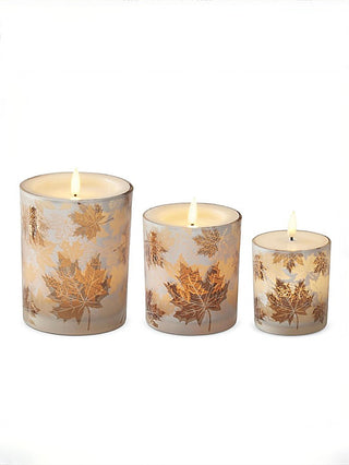Set of three LED glass candles with gold maple leaf print and lit wicks