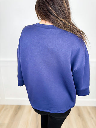 Women’s blue 3/4-sleeve top, back view, loose fit with rounded neckline