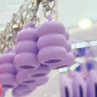 Purple lip gloss cap keychain with metal keyring, close-up of caps